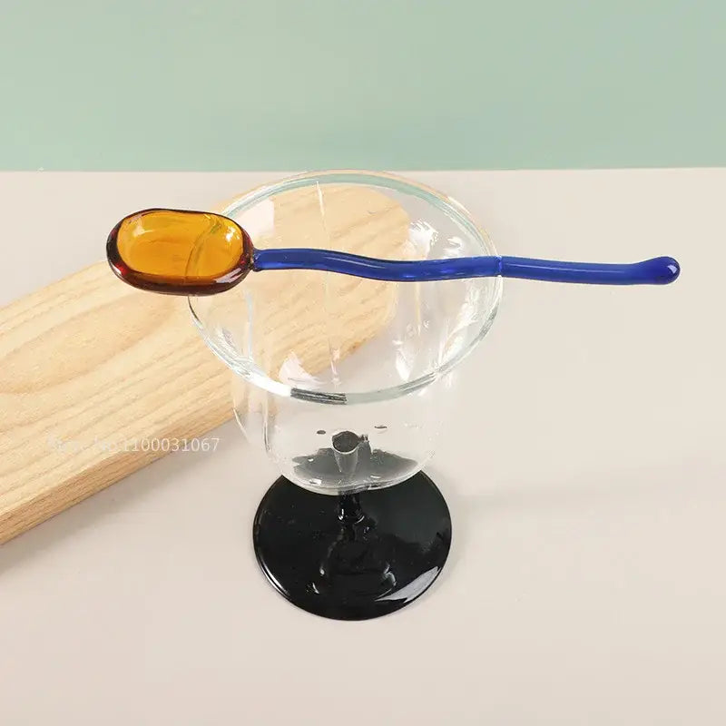 A vibrant blue and amber glass dessert spoon from decorbites glass dessert spoon set resting on a clear stemmed glass