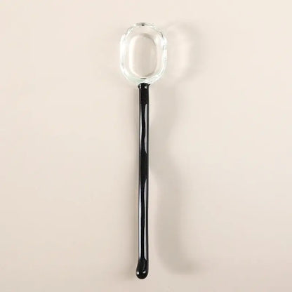 A sleek glass dessert spoon with a transparent bowl and glossy black handle from the decorbites dessert spoon set