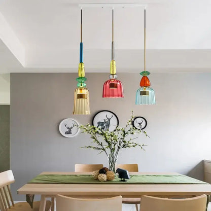 Three colorful glass led pendant chandeliers with metallic accents hang above a kitchen dining table