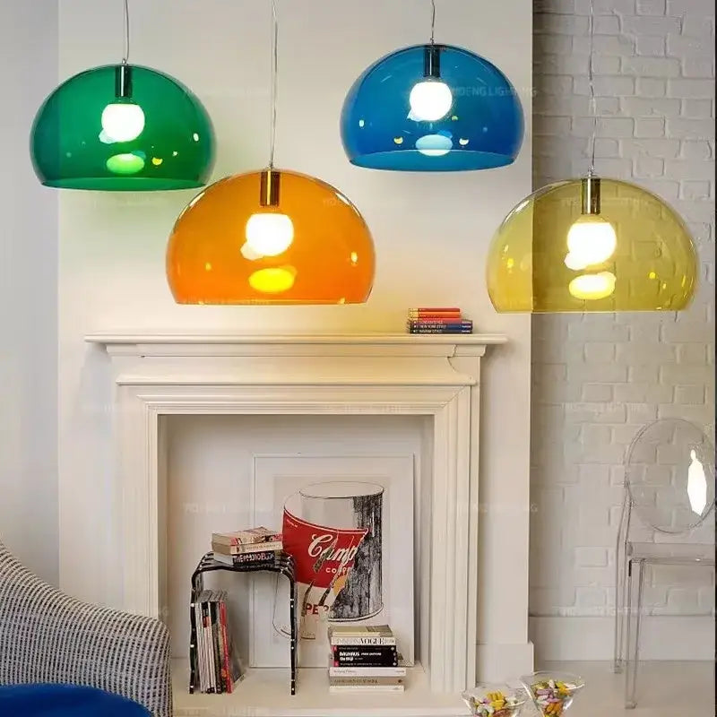 Three modern colorful translucent dome pendant lamps in green orange and yellow hang above a fireplace mantel