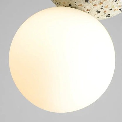 A modern concrete and glass pendant light with an opaque white spherical lampshade and iron finish for dining room use