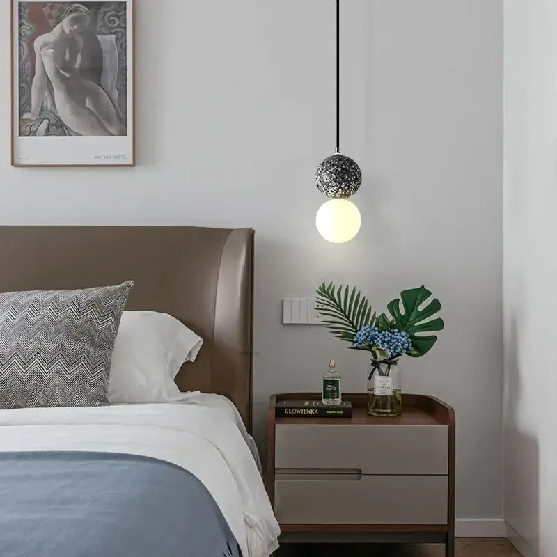 Modern pendant light with a spherical textured black metal shade iron finish and glowing bulb for dining room use