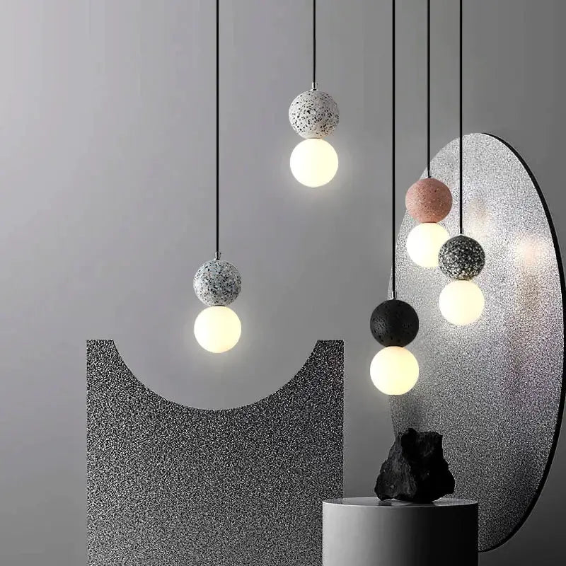 Modern pendant light with speckled concrete spheres and glowing glass orbs in iron finish for dining room use