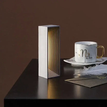Modern concrete stone table lamp with white exterior and golden wood slats emitting warm light for bedroom decorbites concrete stone