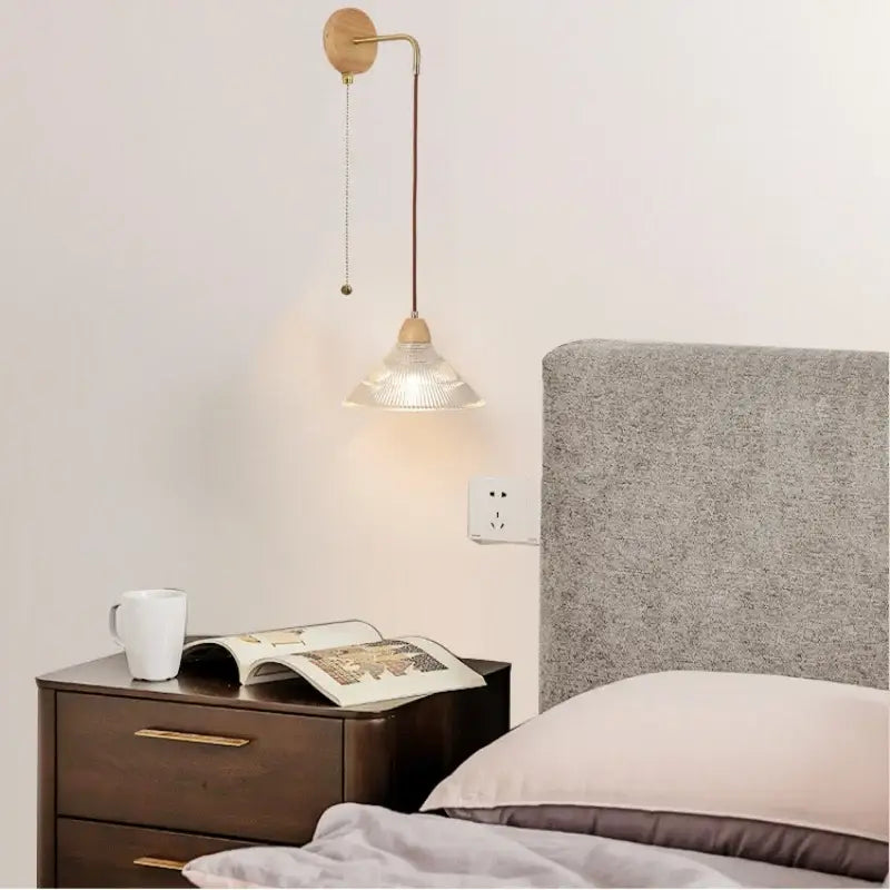 Modern copper and wood wall sconce with clear glass shade and pull chain switch featuring a minimalist brass design