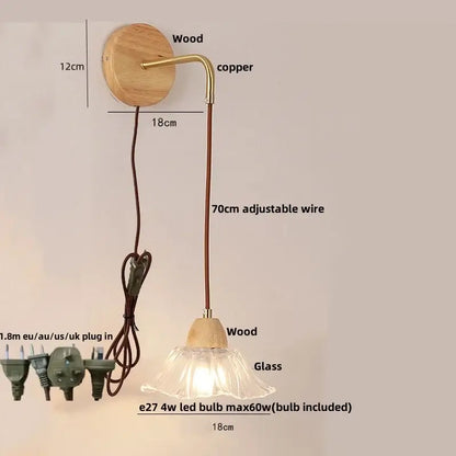 Modern copper and wood wall sconce with clear glass bell shade, brass arm, wooden base, and pull chain switch