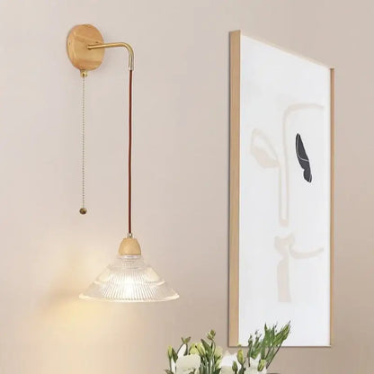 Modern copper and wood wall sconce with brass arm, clear glass shade, and pull chain switch for elegant lighting