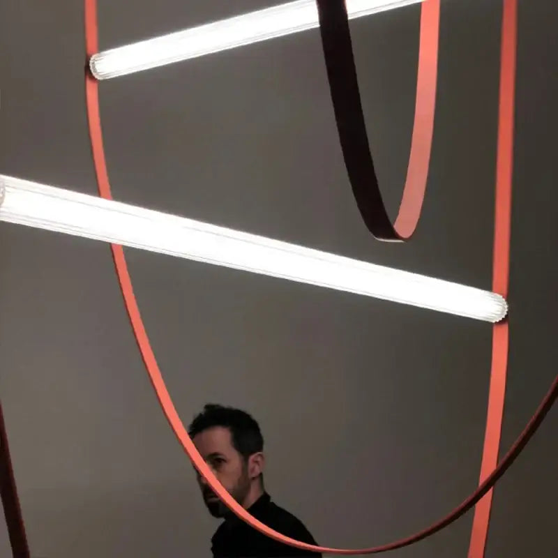 Modern copper leather bell pendant light with intersecting white fluorescent tubes and vibrant orange curved bands decorbites bell pendant