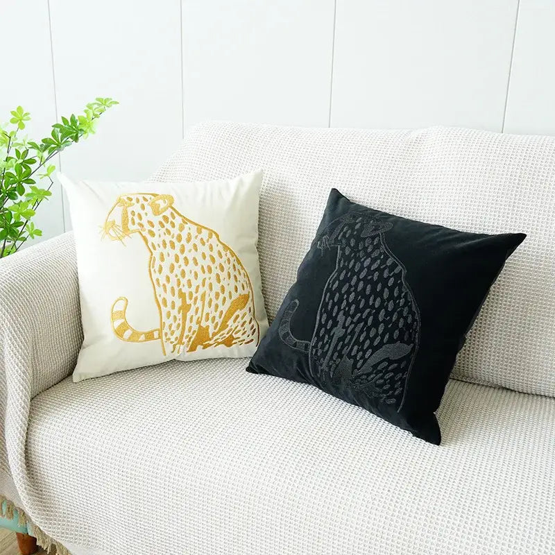 Two decorative throw pillows with embroidered leopard designs in cream and black velvet for home decor and bedroom use