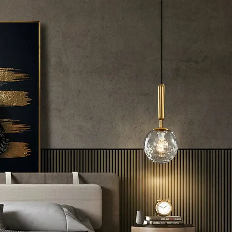 Modern cream and blue glass planet pendant light with gold-toned metal stem and textured globe for bedroom use