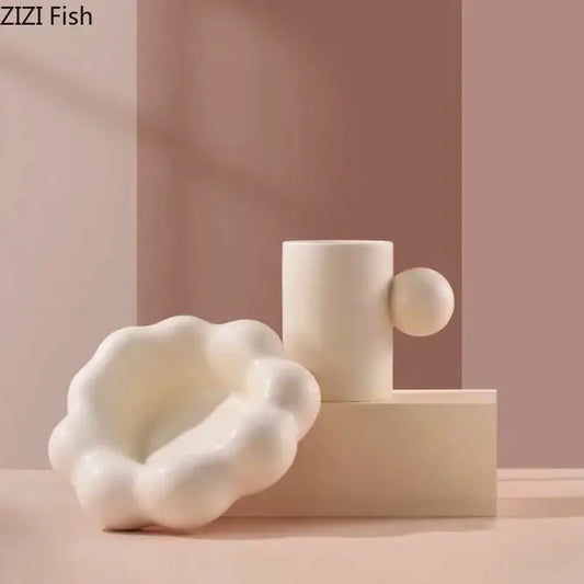Modern cream ceramic cup and saucer set with a cylindrical vase and spherical handle on a cloud base decorbites cotton candy