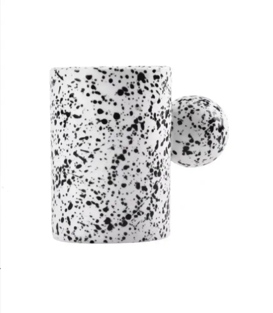 Modern cream ceramic cup and saucer set with white ceramic cup featuring black speckled pattern and spherical handle decorbites cotton candy