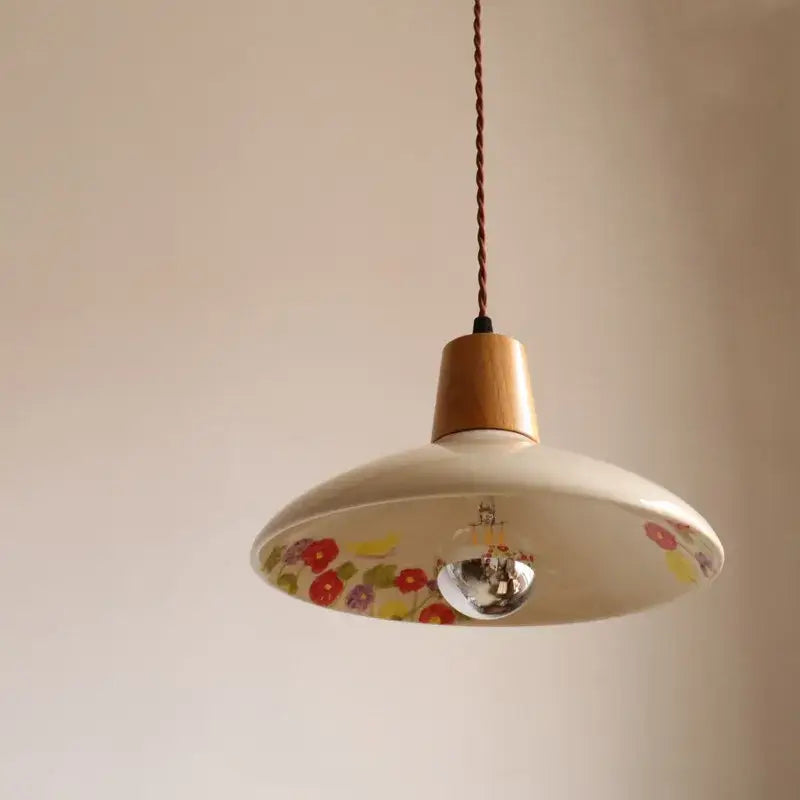 Modern cream ceramic led pendant light with floral patterns and wooden top suspended by twisted brown cord by decorbites ceramic led