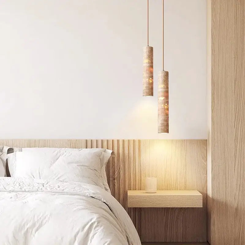 Two modern cream concrete cylindrical pendant lights with warm textured finish provide lighting area above the bed