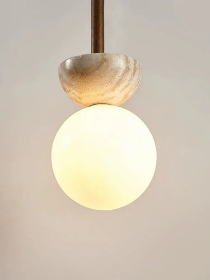 A warm glowing spherical glass pendant lamp with a beige stone textured cap cream style led decorbites bedroom light