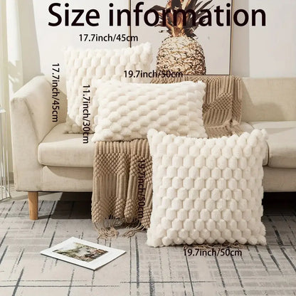 Three off-white plush decorative pillow covers with a raised hexagonal pom pom texture on a beige sofa