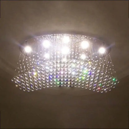 A modern crystal flush mount chandelier with a circular frame and clear glass beads emits bright white light