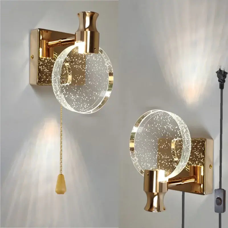 Gold wall lamp featuring a clear circular crystal glass globe filled with sparkling particles for modern bedroom decorbites crystal glass