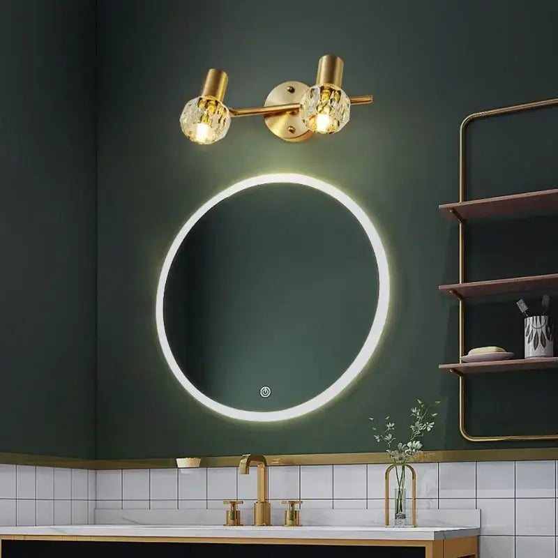 Modern crystal gold wall lamp with gold-toned finish and crystal globe shades illuminating a led-backlit mirror
