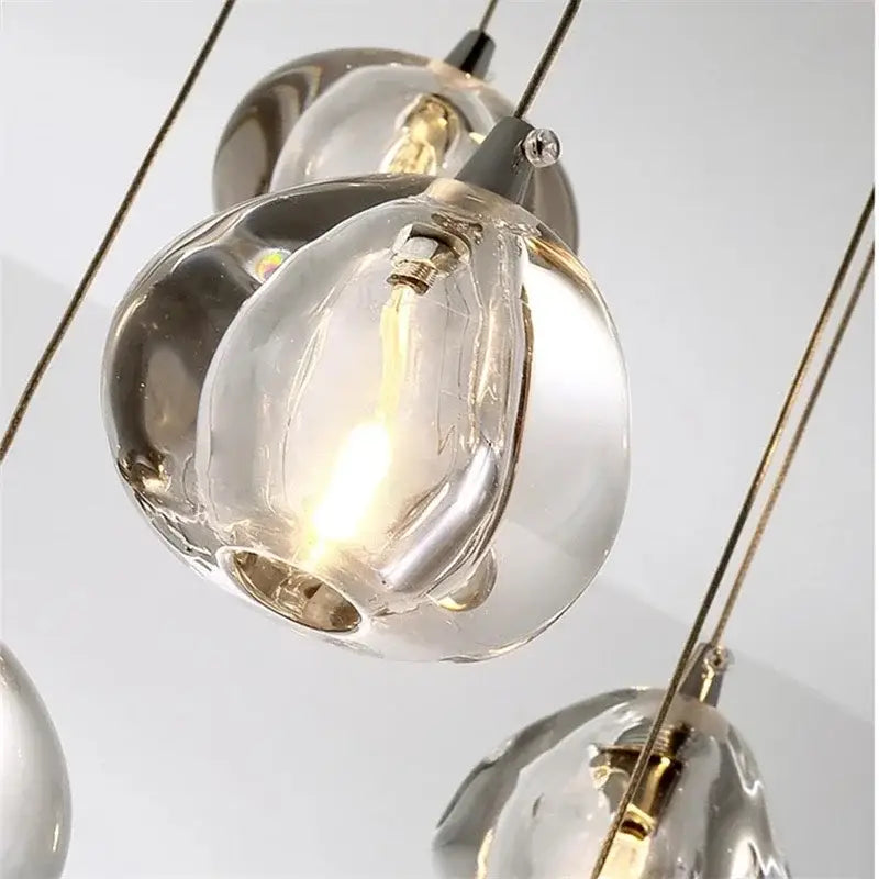 Modern crystal water droplet chandelier with clear hand-blown glass and metallic accents emitting a warm glow