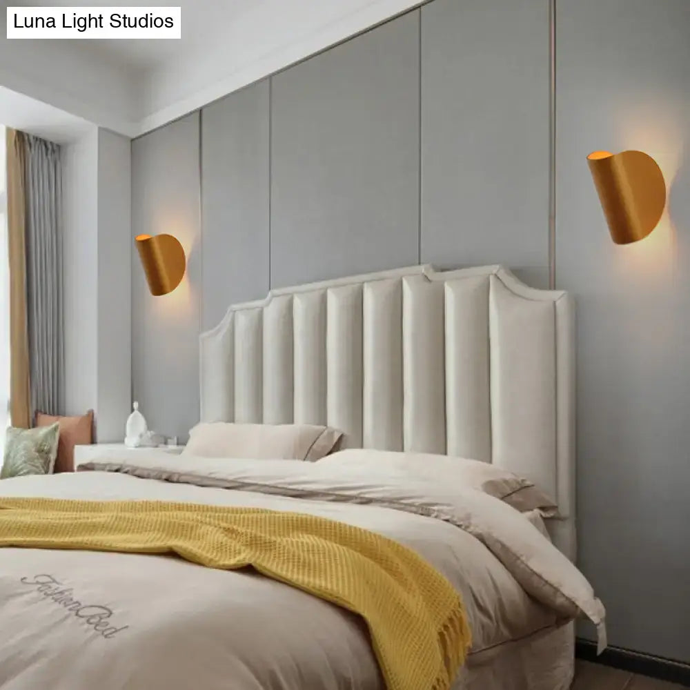 Cream-colored tufted upholstered headboard with vertical channeling and curved top edge under modern curved gold wall sconce light