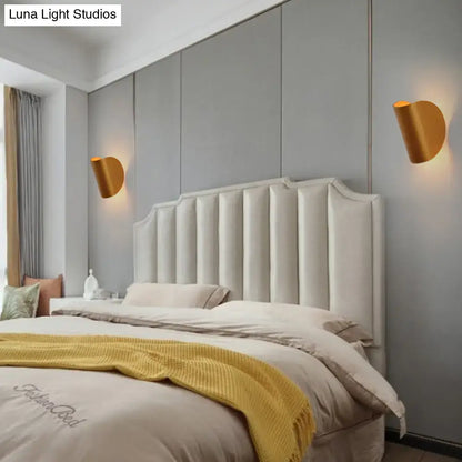 Cream-colored tufted upholstered headboard with vertical channeling and curved top edge under modern curved gold wall sconce light