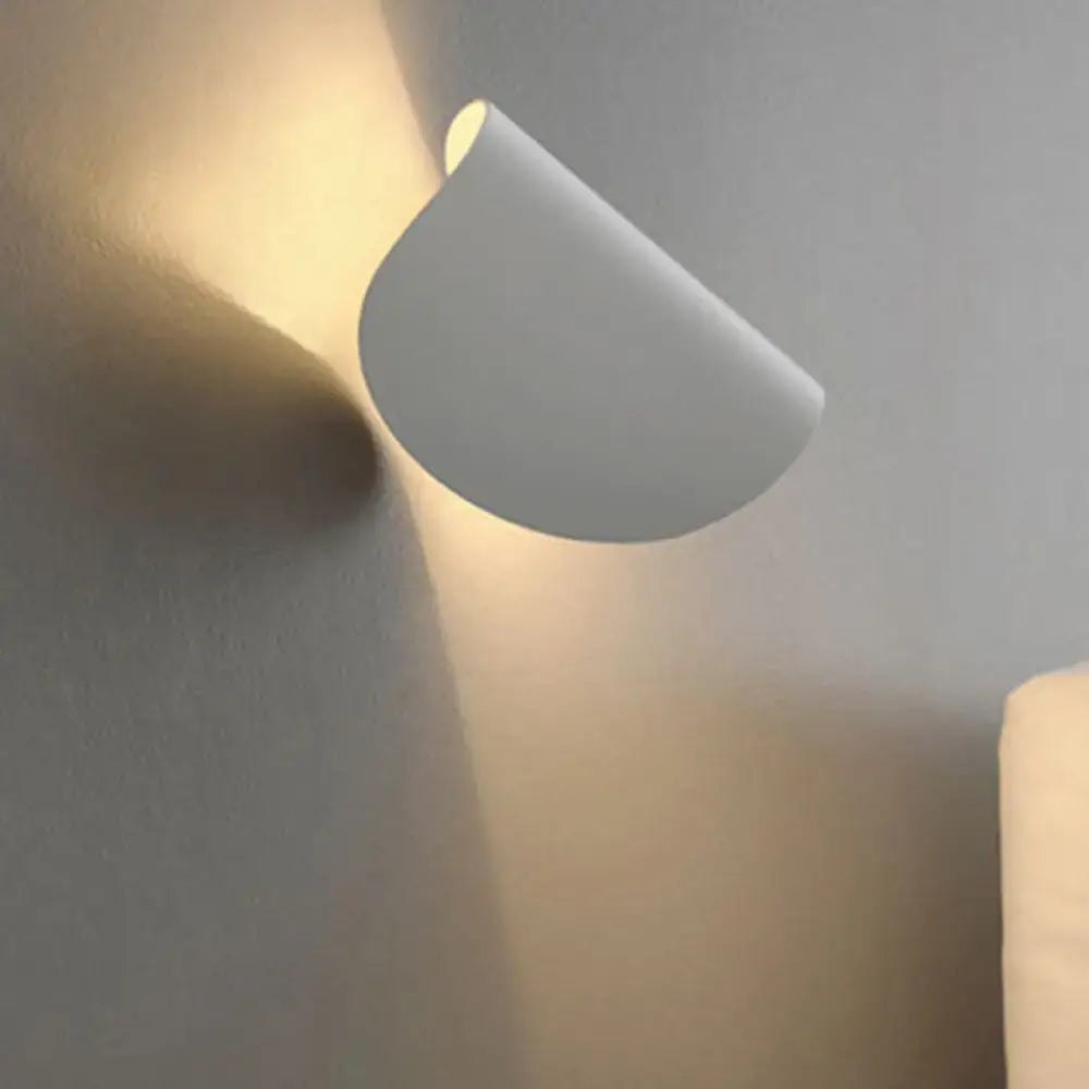 Modern curved gold wall sconce light with sleek minimalist design casting warm ambient light for bedroom use