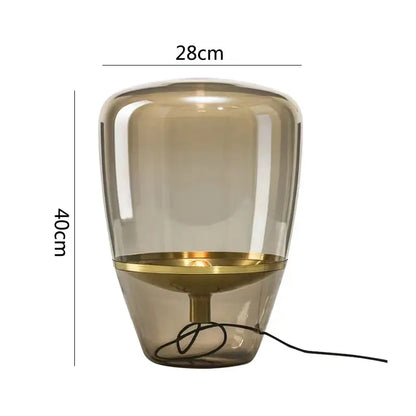 A modern decorbites glass table lamp with a translucent amber glass body and polished brass base for bedroom led lighting