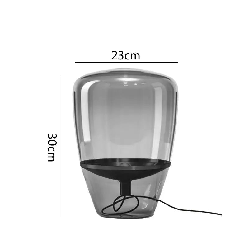 A sleek translucent gray modern cylindrical decorbites glass table lamp with black base and cord for bedroom lighting
