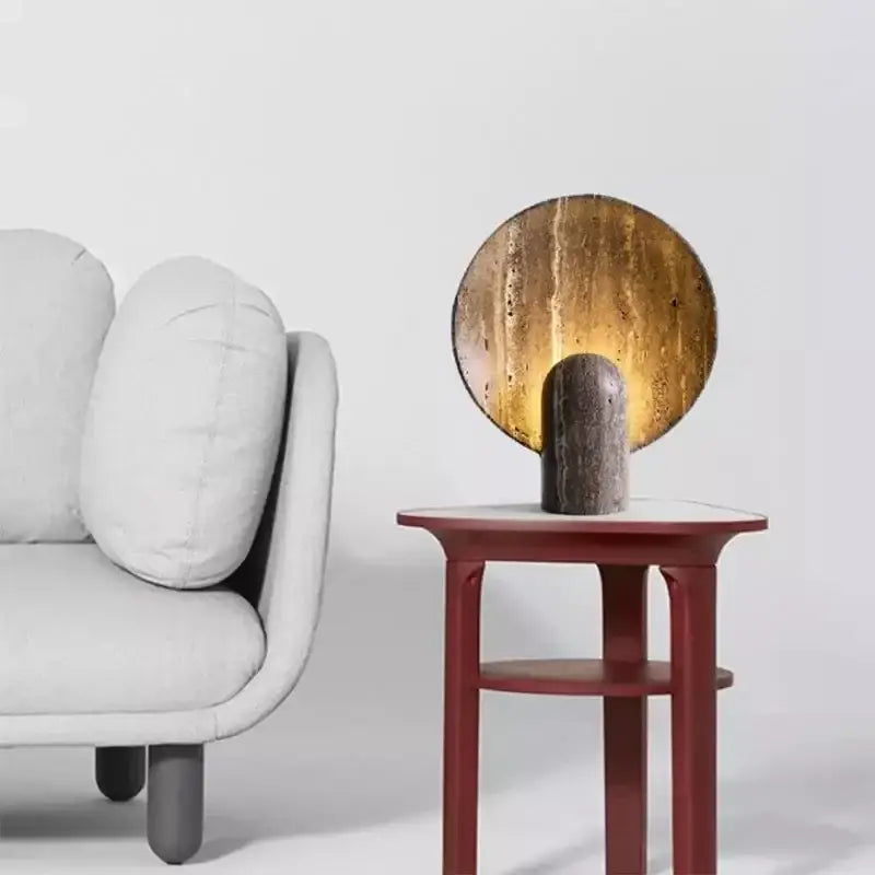 Modern table lamp with textured golden shade and dark travertine rock base for warm bedroom glow