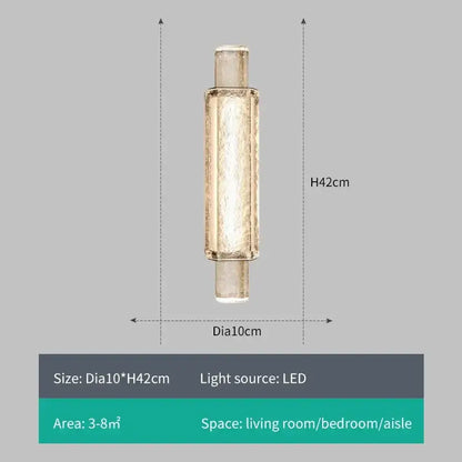 A sleek cylindrical decorbites crystal gold led wall sconce with textured gold metal and frosted glass diffuser