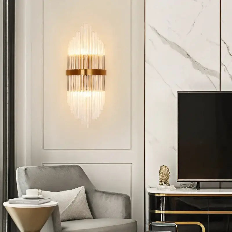 Gold-toned decorbites crystal gold led wall sconce with vertical glass prisms radiating light for modern bedroom decor