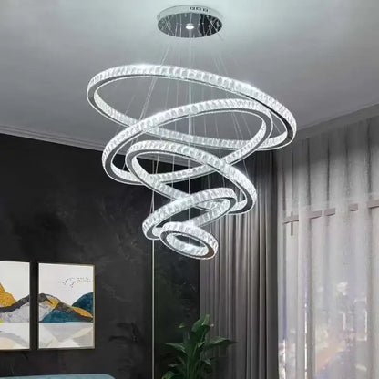 A modern decorbites gold rings crystal chandelier with multiple glowing rings suspended from a circular ceiling mount