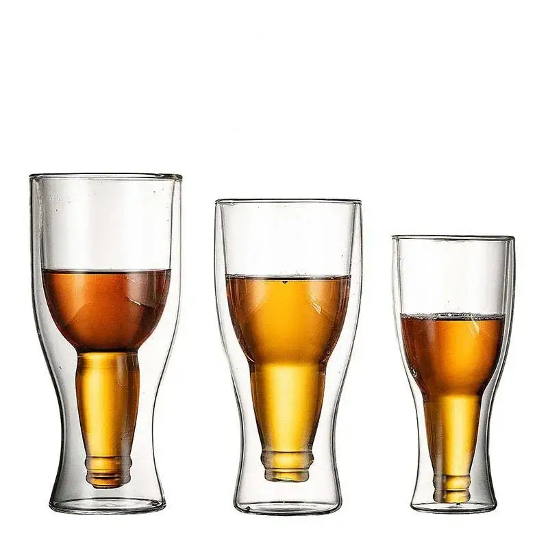 Three clear double wall mugs shaped like bottles filled with amber beer in a modern dining room set