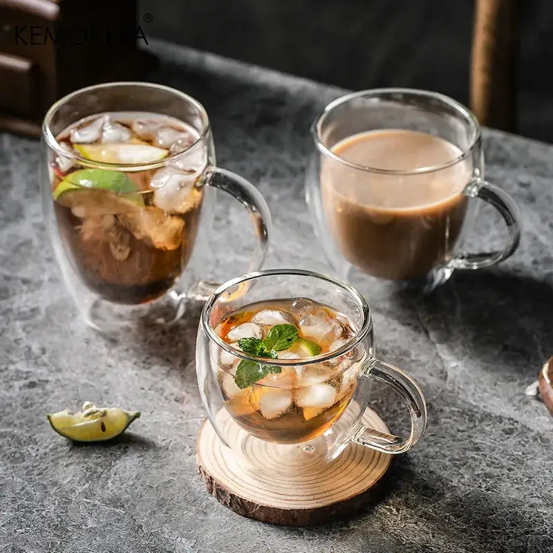 Modern double walled transparent glass cups filled with iced beverages garnished with lime and mint leaves