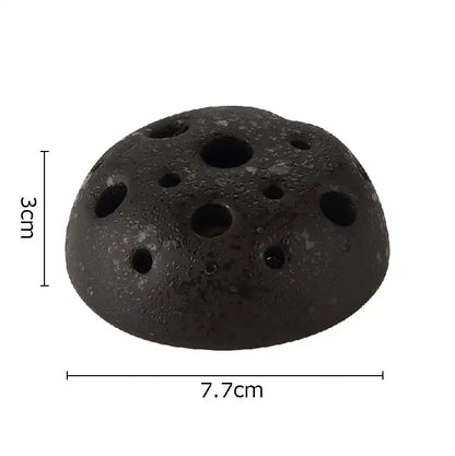 Black porous lotus seedpod ceramic incense burner with circular holes and rough texture for earthy living room decor