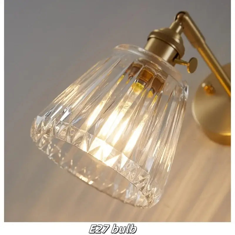 Modern faceted clear glass copper wall lights with a brass-finished metal arm and base for bedroom sconce use