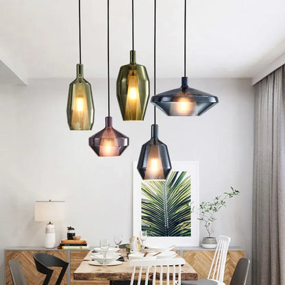Five modern faceted glass pendant lights in olive green amber and dark gray hang above a dining table for home art decor
