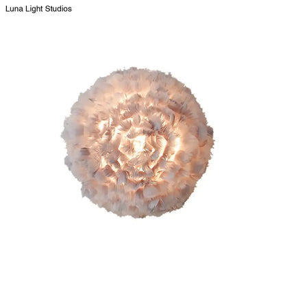 Modern feather material wall light with layered grey and white feathers emitting a warm glow for bedroom use