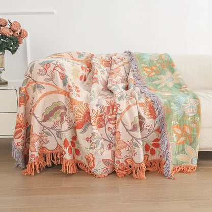 A two-toned peach and mint green decorbites cooling cotton blanket with floral patterns and fringed edges for bedroom decor