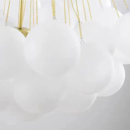 Modern white cloud-shaped pendant lights with frosted glass ball, gold-toned chains, and brass fixture for dining room