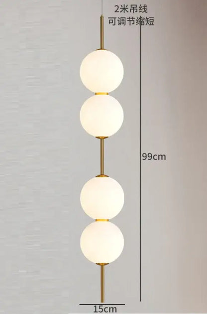 Gold-toned pendant lamp with four frosted white glass ball globes stacked vertically for dining room lighting
