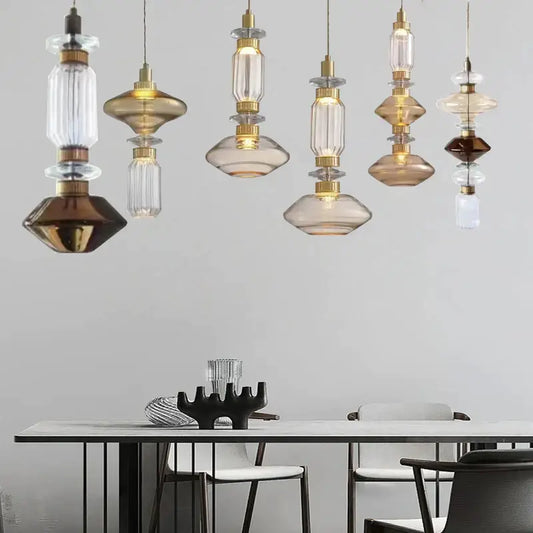 Modern geometric amber and clear glass chandelier with brass accents hanging above a dining table decorbites glass chandelier