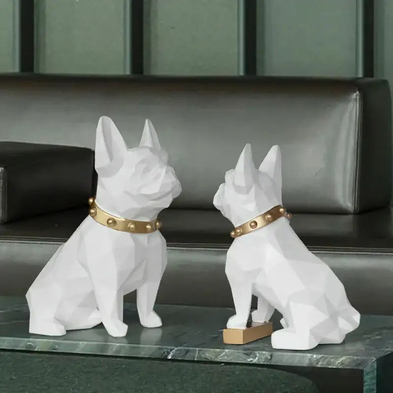 Two white geometric faceted french bulldog figurines with gold studded collars on dark green marble decorbites dog statue