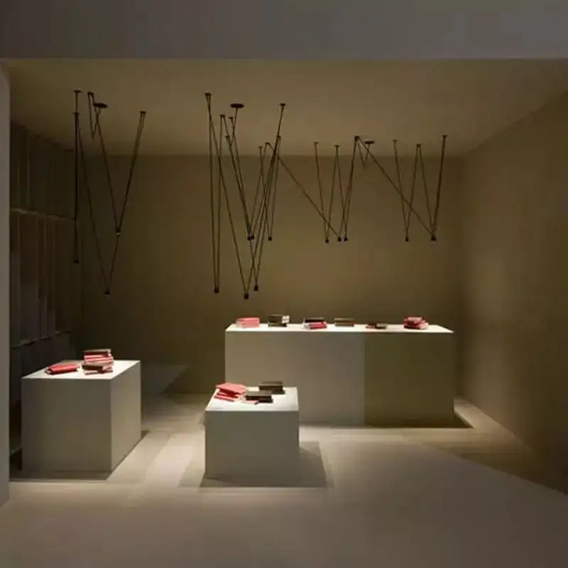The minimalist white display pedestals hold red books under a modern geometric black linear pendant lamp decorbites pendant lamp