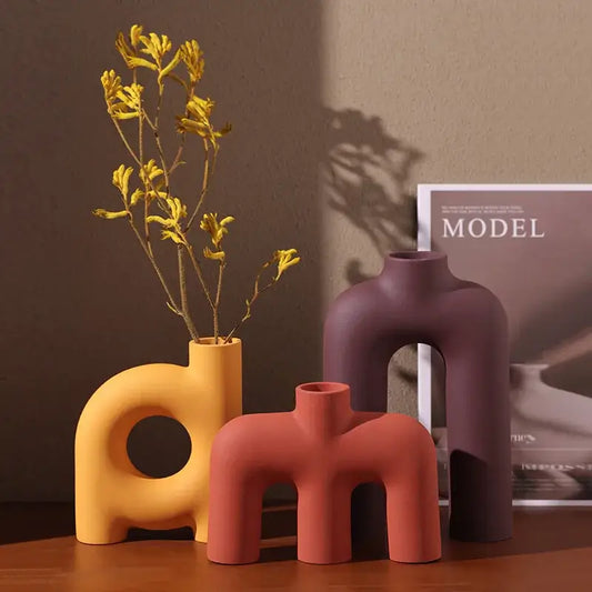 Three bold matte earth tone decorbites geometric ceramic vases in yellow terracotta deep purple with cut-out arches
