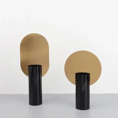 Black geometric cylinder vase with matte gold circular disc at back featuring pink artificial flowers decorbites decor