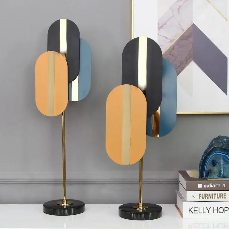 Modern geometric ellipse metal sculpture with stacked black gold and orange panels on brass stands for home decor