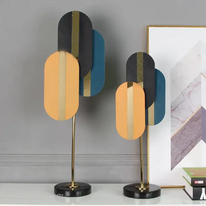 Modern geometric ellipse metal sculpture with layered black gold and teal panels on polished brass stand for home decor