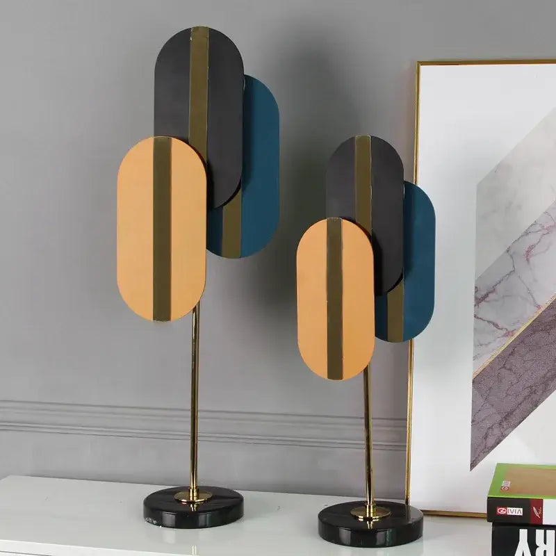 Modern geometric ellipse metal sculpture with layered gold black and teal panels on brass stems for home decor